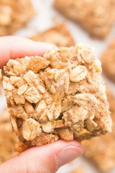 a hand holding a cookie with oatmeal on it in front of other cookies