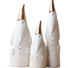 three white ceramic figures with gold colored tops