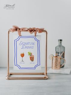 a sign that is on top of a table next to a bottle and glass with a drink in it