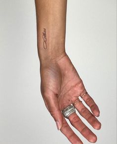 a person's hand with a small tattoo on the wrist and an open ring