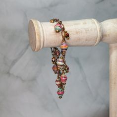 a pair of beaded bracelets hanging from a wooden pole on a marble background