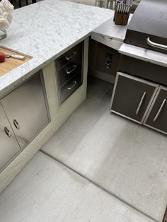 an outdoor kitchen with marble counter tops and stainless steel appliances, along with utensils