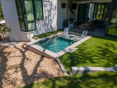 a small pool in the middle of a yard with grass around it and a patio area