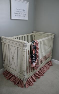 a white crib with pink ruffles in a room