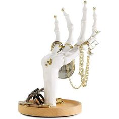 a white sculpture with gold chains on it's legs and hands in the middle