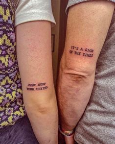 two people with tattoos on their arms that say it's a sign of the times