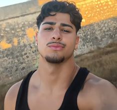 a young man is standing in front of a wall and looking at the camera with an intense look on his face