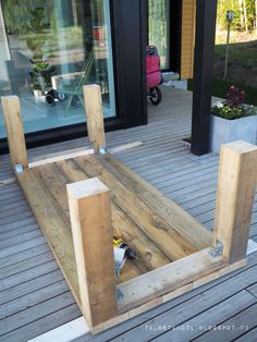 a wooden bench sitting on top of a wooden deck next to a building with glass doors