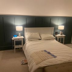 a white bed sitting in a bedroom next to two nightstands with lamps on them