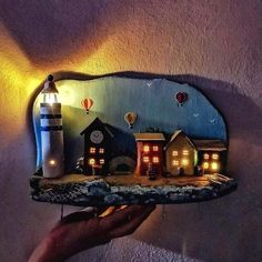 a person is holding up a mirror with lights on it and houses in the background