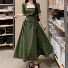 a woman in a green dress standing next to shelves