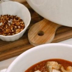 two bowls filled with food sitting on top of a wooden cutting board next to a bowl of rice