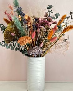 a white vase filled with lots of different colored flowers