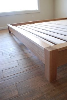 a wooden bed frame on the floor in a room with hard wood floors and white walls