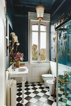 a bathroom with black and white checkered flooring next to a window filled with jewelry