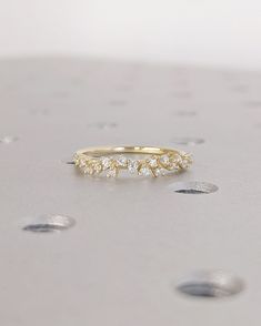 a yellow gold ring with five small diamonds on the side, sitting on top of a table