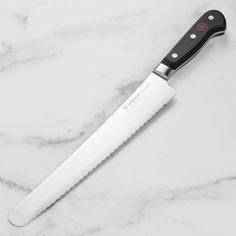 a black and white knife sitting on top of a marble counter next to a bottle