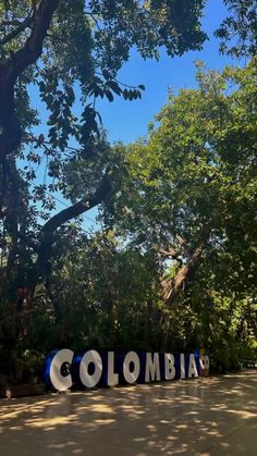 the word colombia is displayed in front of some trees and bushes on a sunny day