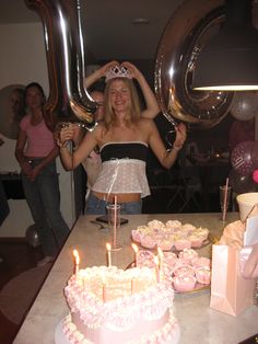 a woman standing in front of a table filled with cupcakes and cake covered cakes