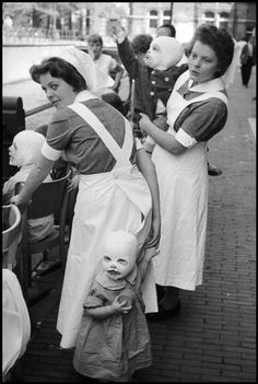 an old black and white photo of some women with dolls on their heads in the street