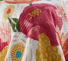 an image of a bed with colorful flowers on the comforter and pillow coverlet