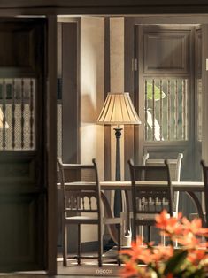 a table and chairs in front of a door with a lamp on top of it