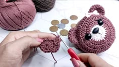 someone is crocheting a teddy bear purse with yarn and scissors on the table