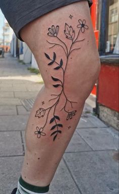 a woman's leg with flowers and stars on it, in front of a building