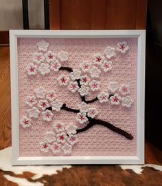 a white frame with pink and white crocheted flowers in the shape of a tree