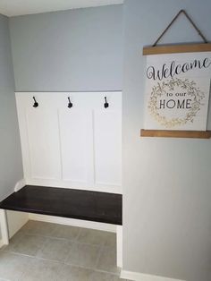 a wooden sign hanging on the wall above a bench in a room with tile flooring