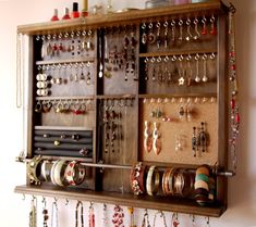 a wall mounted jewelry organizer with lots of earrings on it's sides and hanging from the ceiling