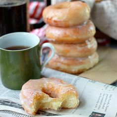 a stack of doughnuts sitting next to a cup of coffee on top of a newspaper