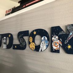 the letters are made out of wood and painted with star wars characters, such as r2d2, droid, bbg, c - 3po, and more