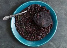 a blue bowl filled with black beans and a spoon on top of the bowl next to it