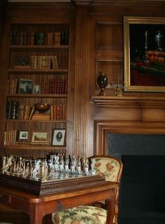 a chess set sitting on top of a wooden table in front of a book shelf