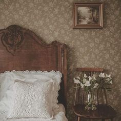 there is a vase with flowers on the bed next to a small table and chair