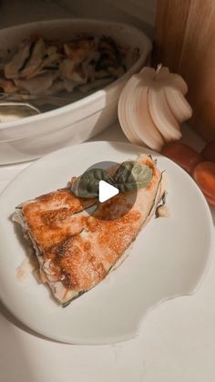 a piece of pizza sitting on top of a white plate next to a bowl of vegetables