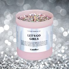 a pink candle with glitter on it sitting in front of some silver and white lights