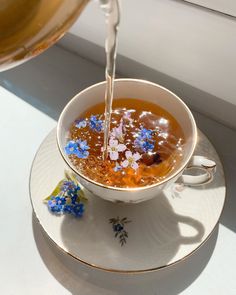 a tea cup filled with liquid being poured into it on top of a saucer