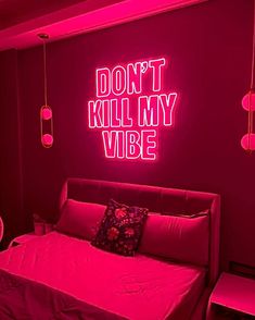 a bed in a room with neon lights on the wall and a pink light above it that says, don't kill my vibe