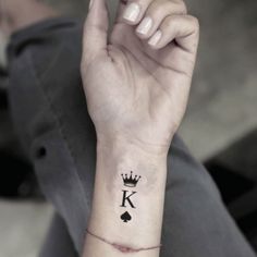 a person with a tattoo on their wrist holding up the letter k in front of them