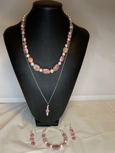 Gorgeous four piece set made of pink matrix jasper and silver lava stone. Necklace is 20 inches long with a magnetic clasp. Bracelet is 7-1/2 inches with a magnetic clasp. The earrings are 1-1/2 inches. The fourth piece drop pendant is 24 inches long. Suitable for any occasion. Adjustable Handmade Pink Jewelry Sets, Adjustable Double Strand Pink Jewelry, Silver Jewelry With Natural Stones And Rhodonite, Silver Rhodonite Jewelry With Natural Stones, Lava Stone Necklace, Jasper Jewelry, Clasp Bracelet, Earring Holder, Christmas Earrings