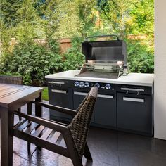 an outdoor kitchen with grill, table and chairs