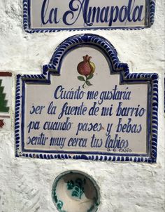 two signs on the side of a building with blue and white trimmings, in spanish