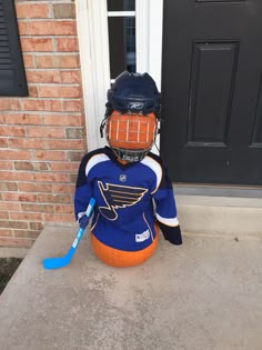 a hockey goalie sitting in front of a door wearing a blue jersey and helmet