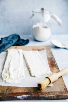 a wooden cutting board topped with lots of white cheese next to a brush and cloth