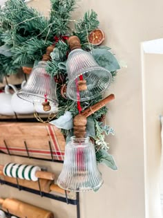 bells hanging from the side of a wall with greenery and other items on it