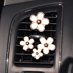 an air vent in the center console of a car with three flowers on each side