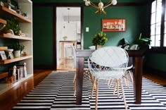 a dining room with green walls and black and white rug