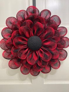 a red and black mesh flower hanging on the front door